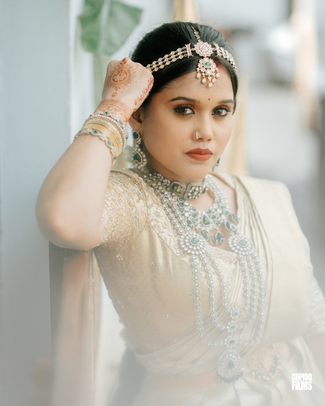 A bride in white and emerald wedding jewellery
